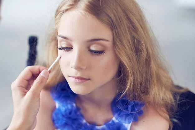 Stylist doing the make-up for a beautiful little girl model. Close-up image.