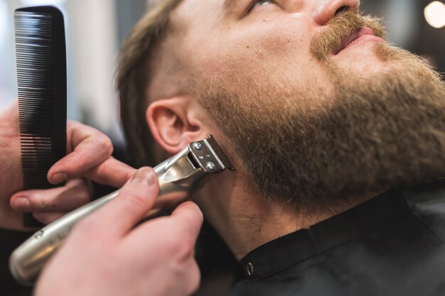 Stylist trimming beard of client