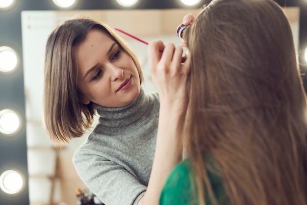 Foto gratuita stilista con eyeliner su modello anonimo