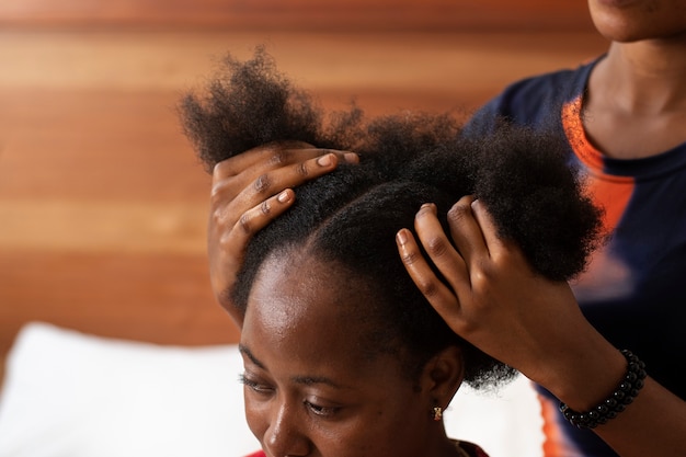 クライアントのアフロヘアーの世話をしているスタイリストの女性