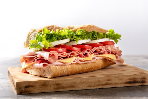 Submarine sandwich with ham cheese lettuce tomatoesonion mortadella and sausage on wooden table