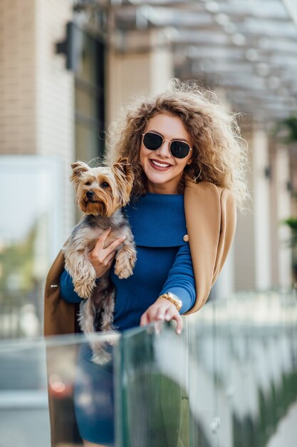 Successful attractive woman wearing at nude coat holding Yorkshire terrier