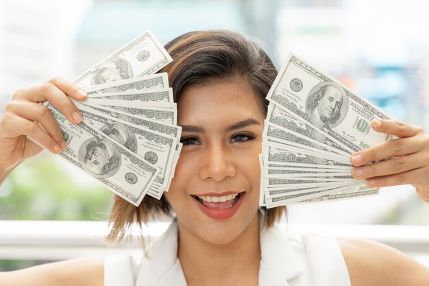 Successful beautiful Asian business woman holding money US dollar bills in hand 