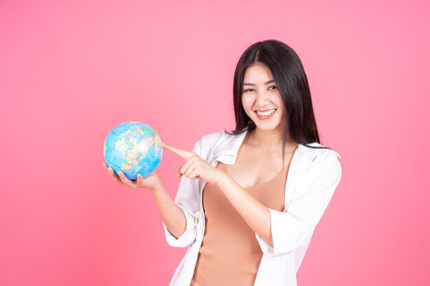 분홍색 배경에 손에 세계 세계지도의 빈티지지도를 들고 성공적인 아름다운 아시아 비즈니스 젊은 여자