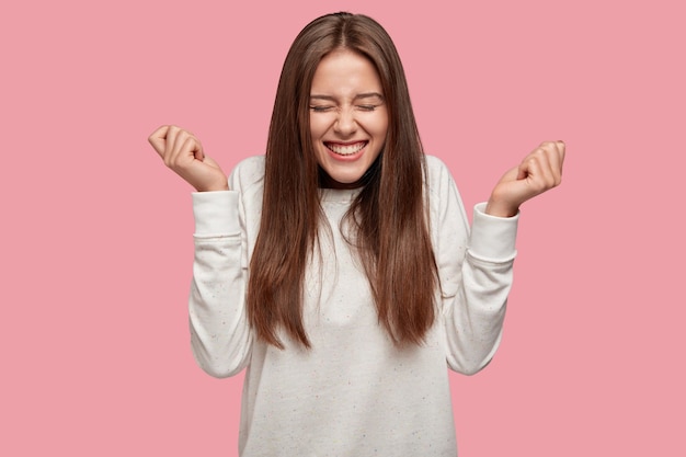 Free photo successful beautiful brunette posing against the pink wall