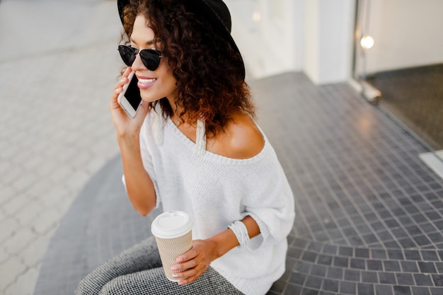Успешная негритянка, блоггер или менеджер магазина разговаривает по мобильному телефону во время перерыва на кофе.