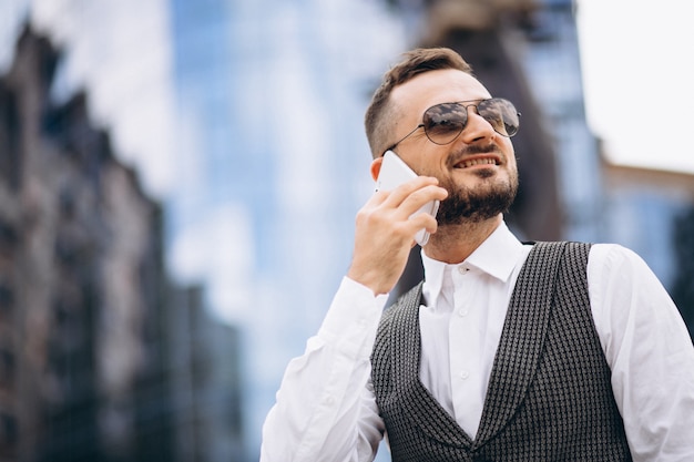 Uomo d'affari di successo dal grattacielo parlando al telefono