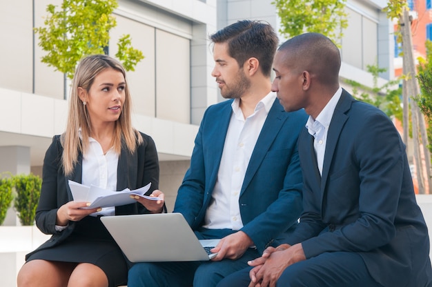 Successful business people discussing reports outdoors