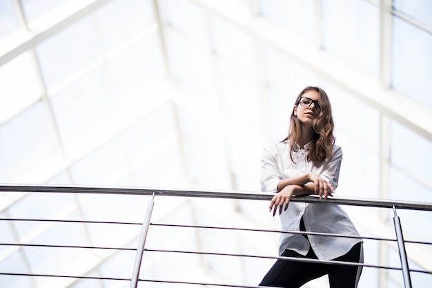 Successful business women standing looking through on balcony in modern office centre dressed up in white t-shirt