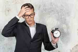 Free photo successful businessman in formal wear pointing at clock