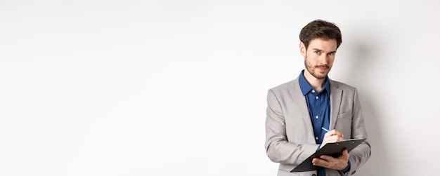 Free photo successful businessman in grey suit taking notes working in office clothing holding clipboard and lo