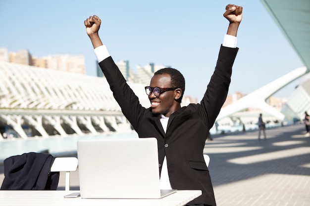 Successful businessman raising his hands having cheerful expression after signing contract