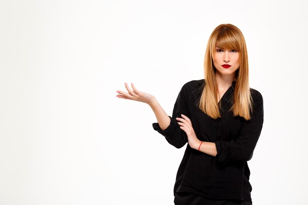 Successful businesswoman pointing hand in side over white wall