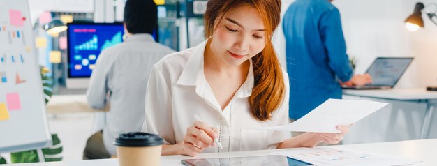 성공적인 임원 아시아 젊은 사업가 스마트 캐주얼 드로잉, 쓰기 및 현대 홈 오피스에서 영감 검색 아이디어 작업 과정의 디지털 태블릿 컴퓨터 생각 펜을 사용하여 착용하십시오.