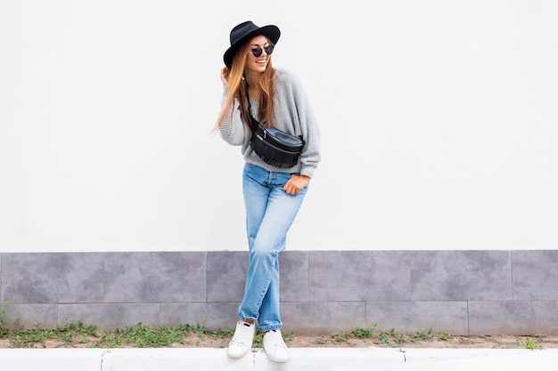 Free photo successful  exited stylish girl with candid smile posing on white urban wall