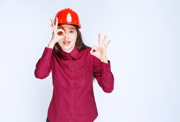 확인 표시를 주는 빨간색 하드 헬멧에 성공적인 여성 건축가.