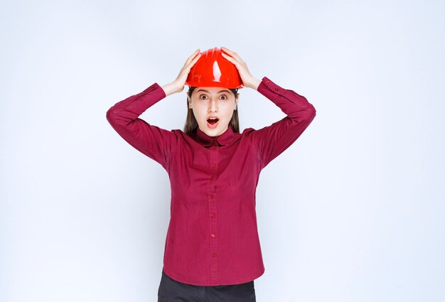 欲求不満から彼女の頭を保持している赤いヘルメットで成功した女性建築家。