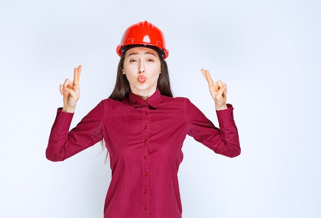 빨간색 하드 헬멧에 서서 표지판을 주는 성공적인 여성 건축가.