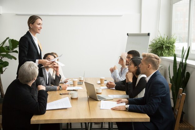 Successful female boss leading team meeting talking to multiracial employees