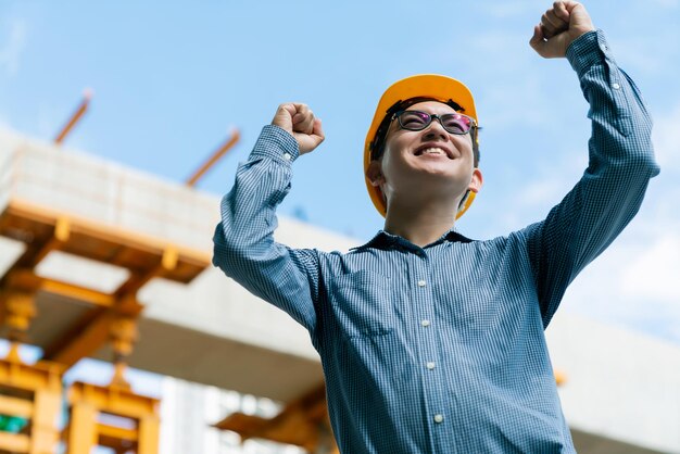 Successful handup smart asian engineer manager with safety uniform checking site construction with steel and concrete structure background