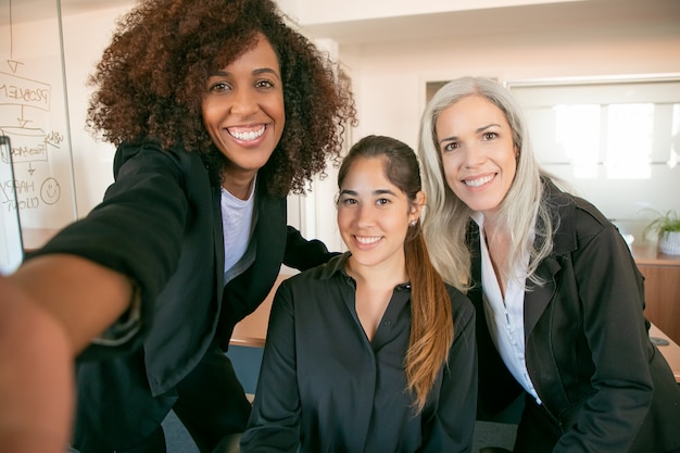 함께 사진을 위해 포즈를 취하는 성공적인 행복 사무실 팀. 자신감이 아름다운 경제인 또는 회의실에서 셀카를 복용 여성 관리자 미소. 팀워크, 비즈니스 및 관리 개념