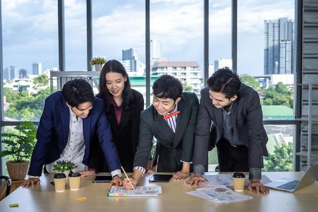 Successful happy workers group of asian business partners with diverse genders (lgbt) see and pointing at it at meeting a successful business plan on data summary paper in the room at office