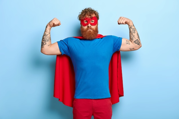 成功したヒーローは赤いマスクとマントを着て、腕を上げます