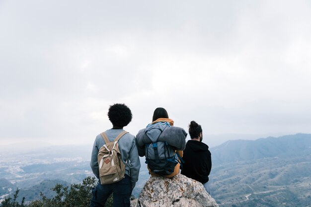 Успешные друзья путешественника наслаждаются видом на вершину горы