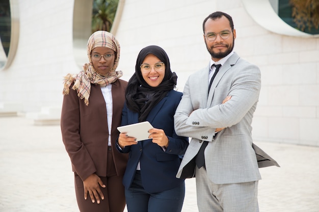 Free photo successful interracial business team with tablet posing outside