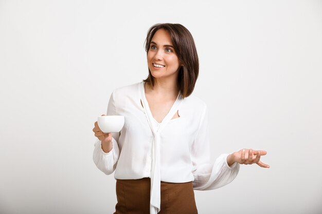 Successful lady boss drinking coffee, talking to coworker