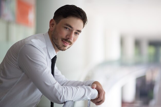 Successful male manager leaning on railings