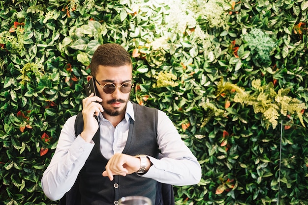 Foto gratuita uomo di successo che parla al tempo di controllo del telefono