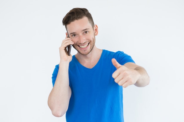 Uomo di successo utilizzando il telefono e mostrando thumb-up