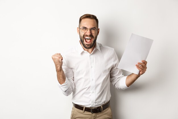 Successful manager making fist pump, rejoicing of work and showing documents, standing over white background, winning case.