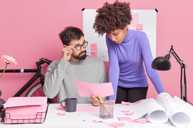 Successful partnership collaboration and teambuilding concept. Busy male boss and female employee discuss future architectural project share experience with each other pose in coworking space