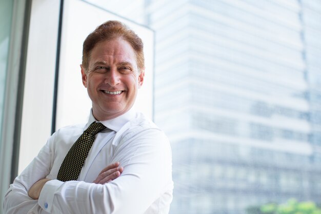 Successful senior businessman standing at window