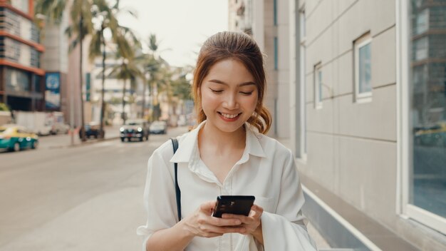 스마트 폰을 사용하고 문자 메시지를 입력하는 패션 사무실 옷에서 성공적인 젊은 아시아 사업가