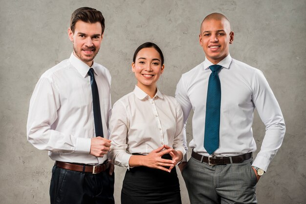 Successful young business partners looking to camera standing against grey wall