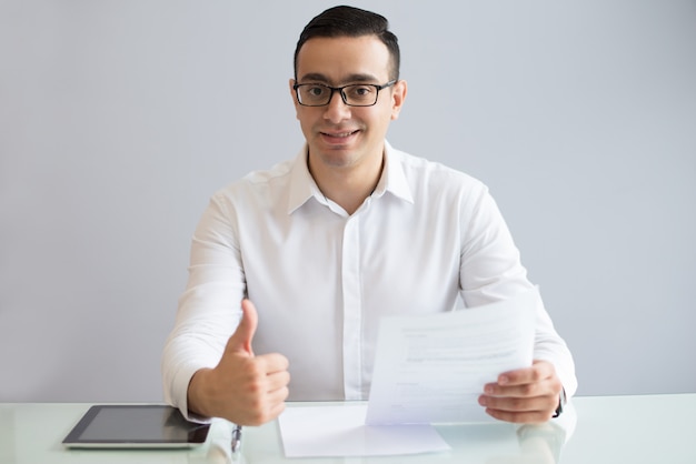 Successful young businessman with document showing thumbs up