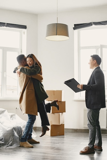 Successful Young Couple Becoming Homeowners. Girl Jumps Into His Boyfriend's Arms Hug. Spacious Bright Home with Big Windows.