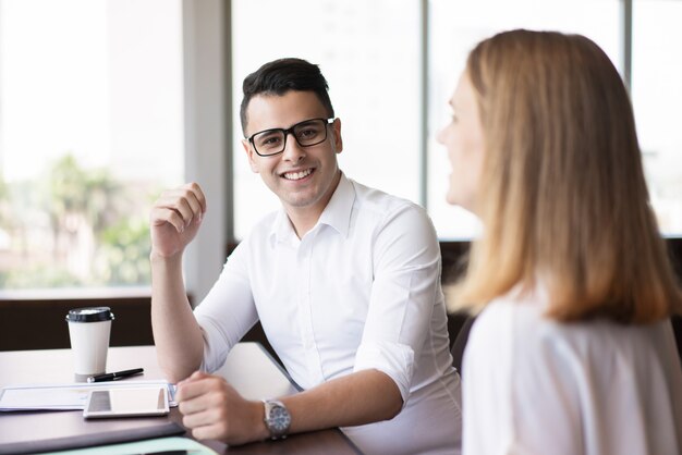 Successful young executive sitting at table with female colleague. 