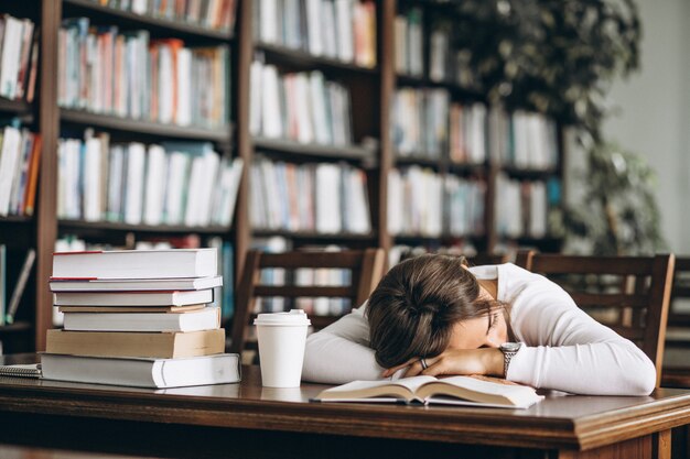 テーブルの上の図書館で寝ている学生