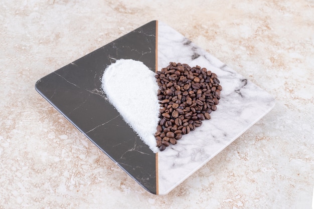 大理石のプレートにハートの形に配置された砂糖とコーヒー豆