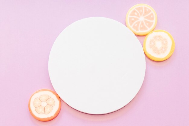 Конфеты из сахарного желе с белой пустой круговой рамкой на розовом фоне