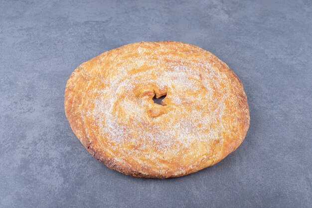 Sugar powder over bread on marble table.