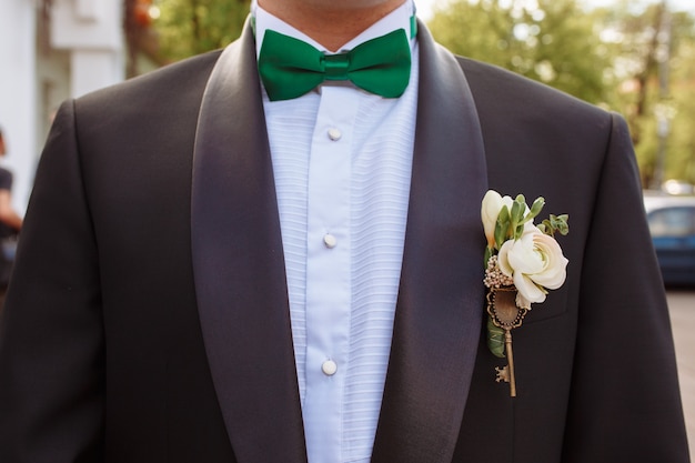緑色の蝶ネクタイとブートンニエールと新郎のスーツ