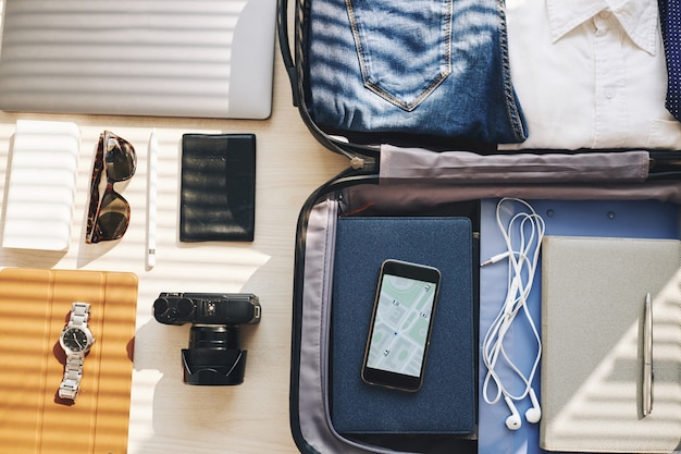 Suitcase, electronic devices and personal belongings arranged for business trip