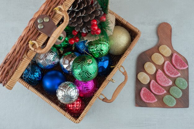 Чемодан, полный рождественских шаров и деревянная доска с мармеладом на белом фоне. Фото высокого качества