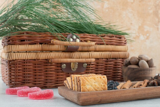 A suitcase and wooden board full of crackers, star anise and cinnamon sticks on marble background. High quality photo