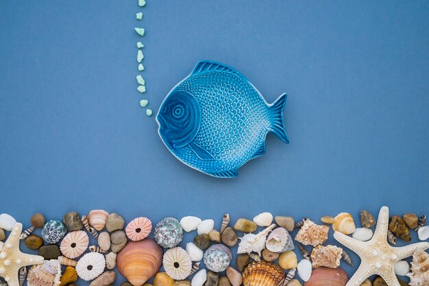 Summer composition with blue fish and variety of seashells